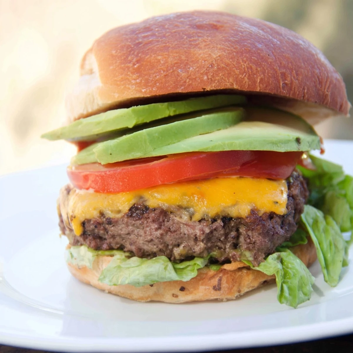 Close-up of a flavorful beef burger with avocado, showcasing layers of texture and savory appeal.