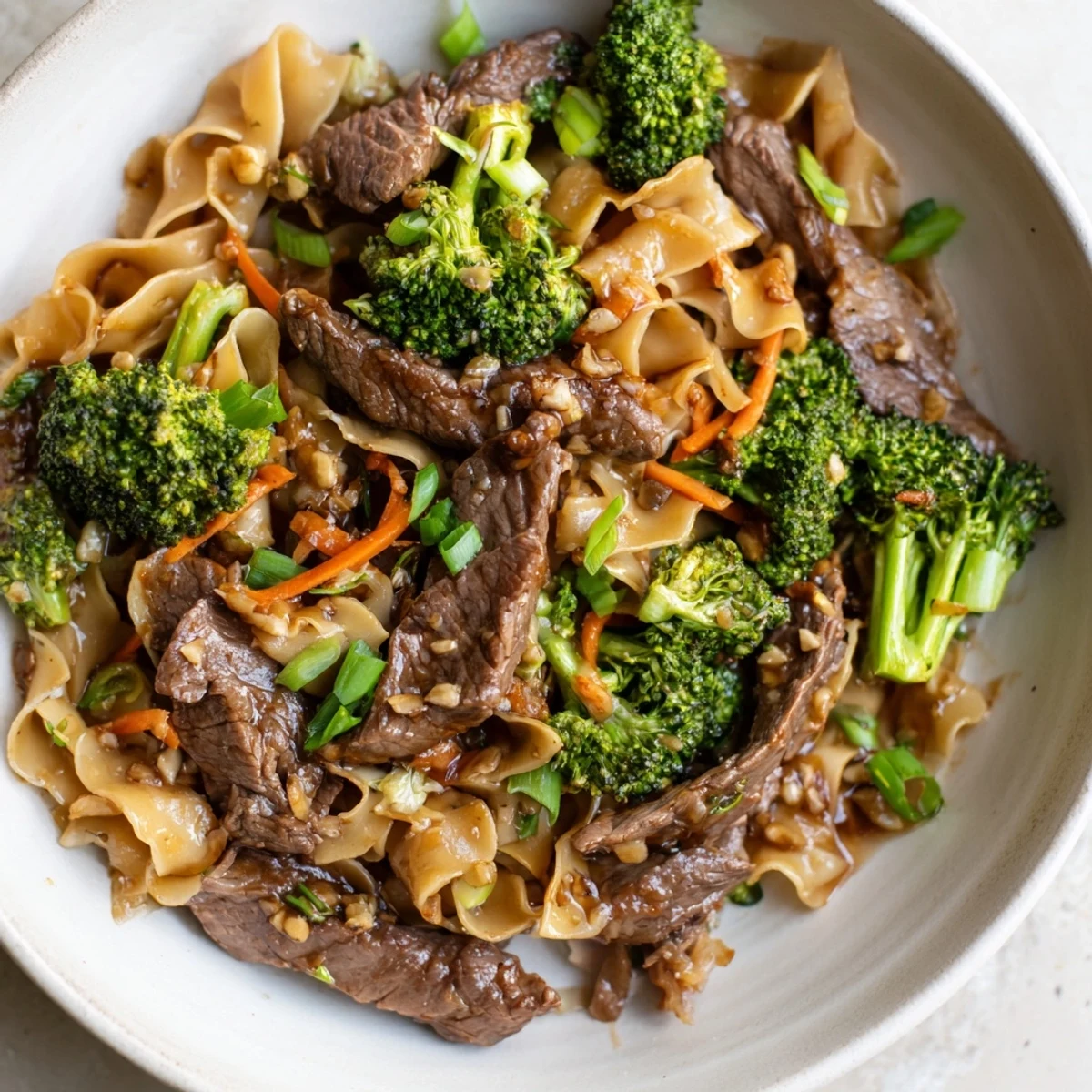 Beautifully plated Beef and Broccoli Noodles, offering a comforting aroma with a rich, flavorful sauce and fresh scallions.