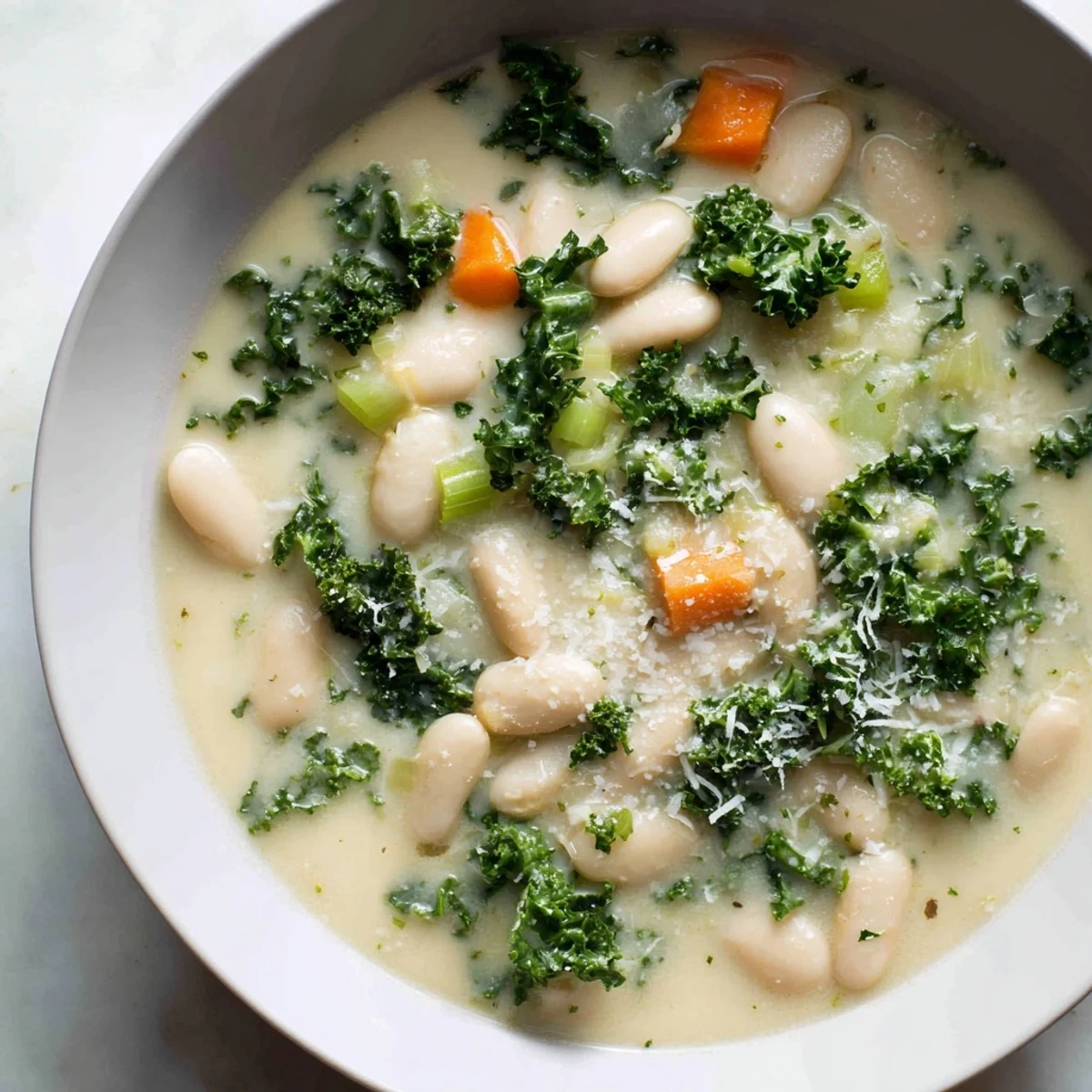 A bowl of savory, vibrant creamy white bean and kale soup, ready to be enjoyed with crusty bread.