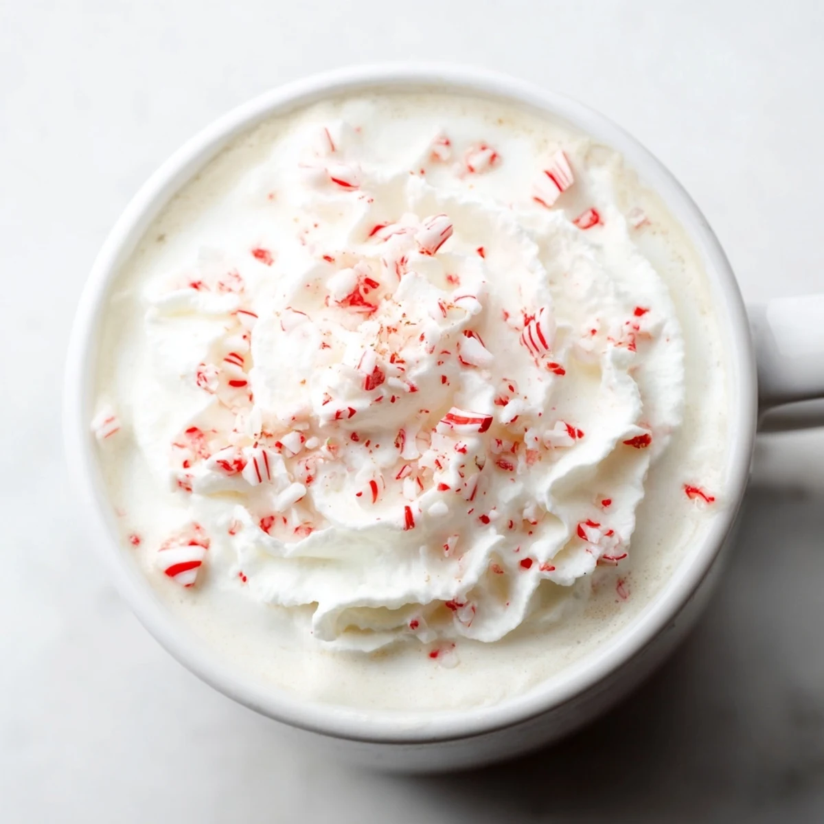 Steaming Peppermint Hot Drink, topped with whipped cream and crushed candies, perfect winter warmer.