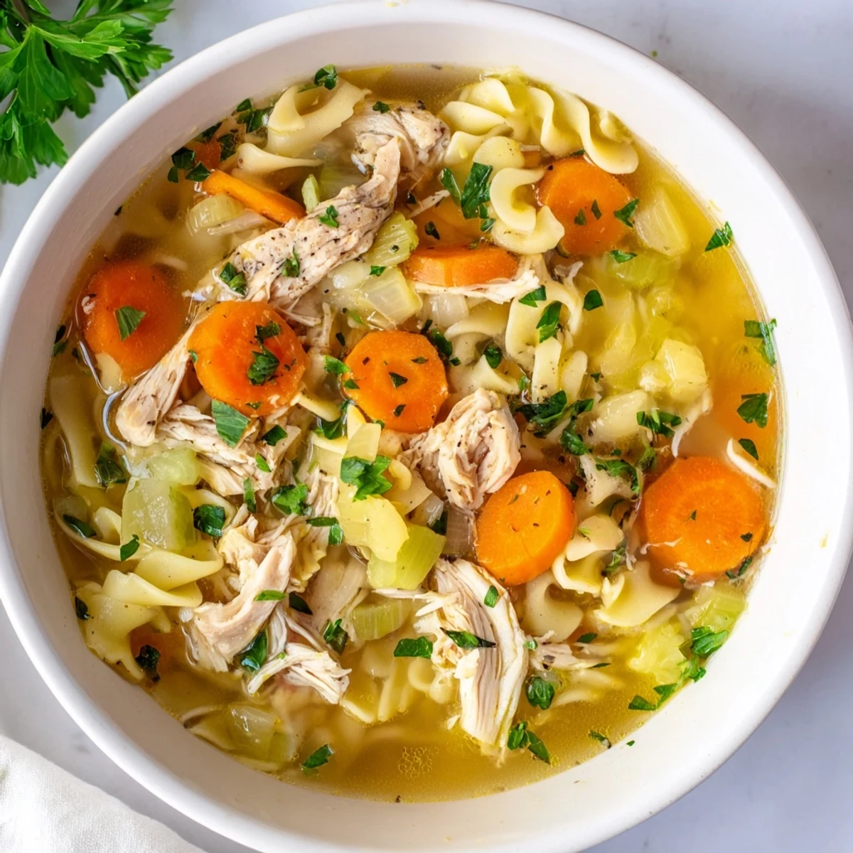 Steaming bowl of homemade chicken noodle soup filled with tender chicken and veggies.