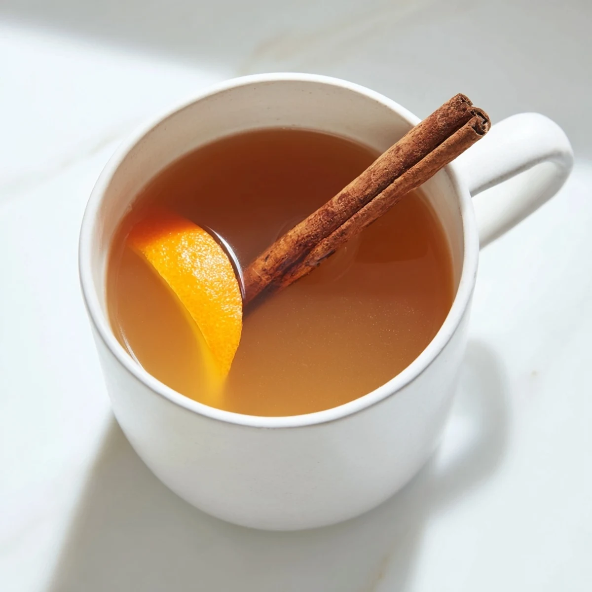 Warm Cider Spiced with floating spices in a rustic pot, ready for cozy evenings.