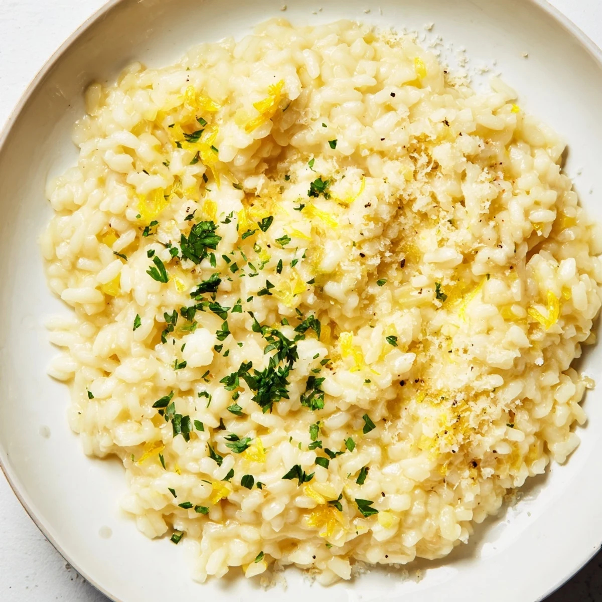 A steaming bowl of creamy risotto, glistening with Parmesan, ready to serve on a plate.