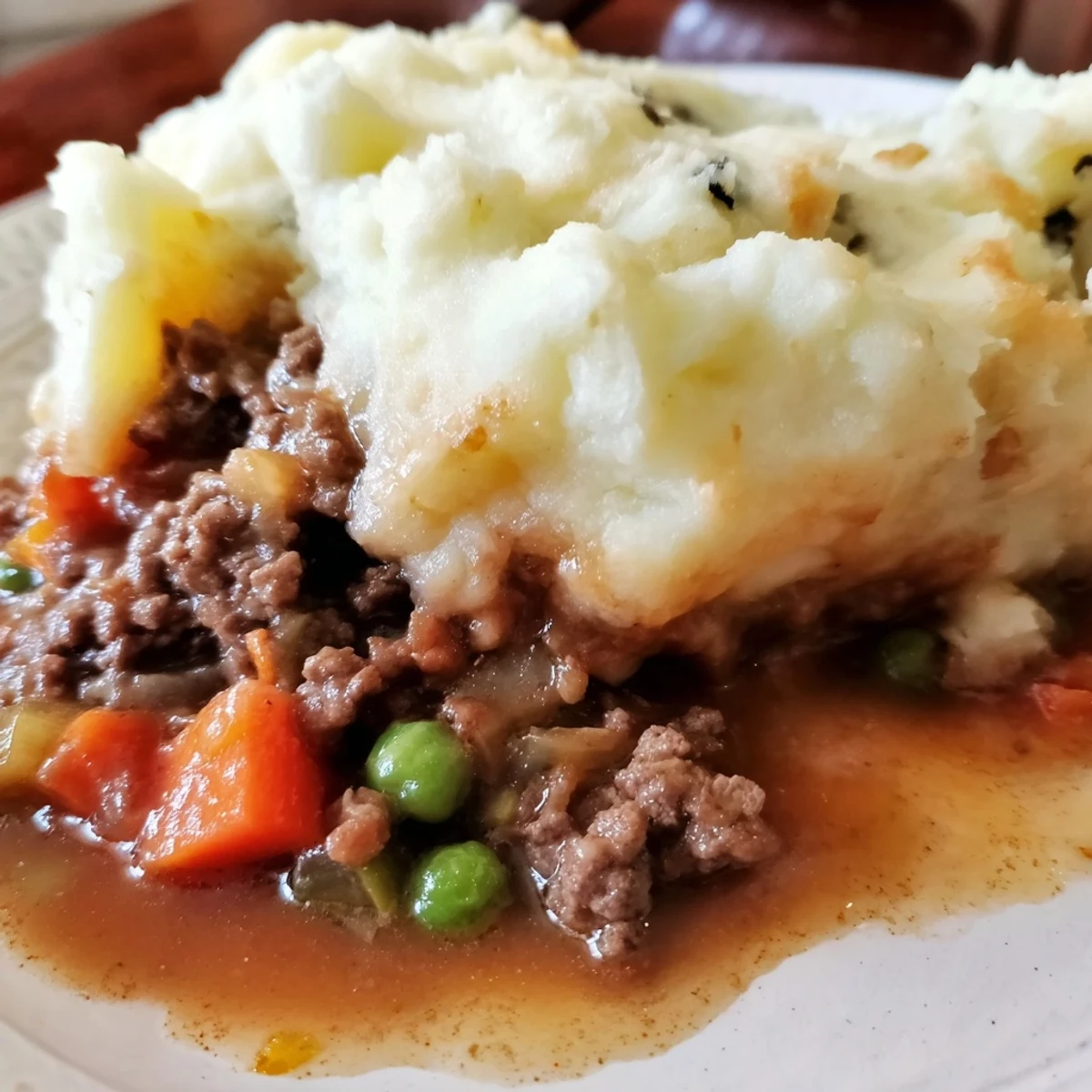 A close-up of Classic Beef Cottage Pie reveals a bubbling beef gravy and fluffy mashed potato topping.
