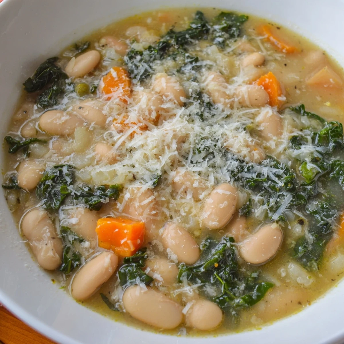 A ladle serving Creamy White Bean and Kale Tuscany Soup from a pot, revealing the creamy texture of the broth.