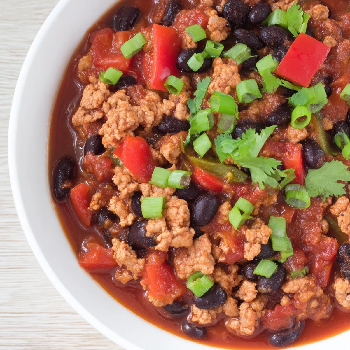 Comforting bowl of Turkey Chili with Black Beans and Tomatoes with melted cheese and a warm side of cornbread.