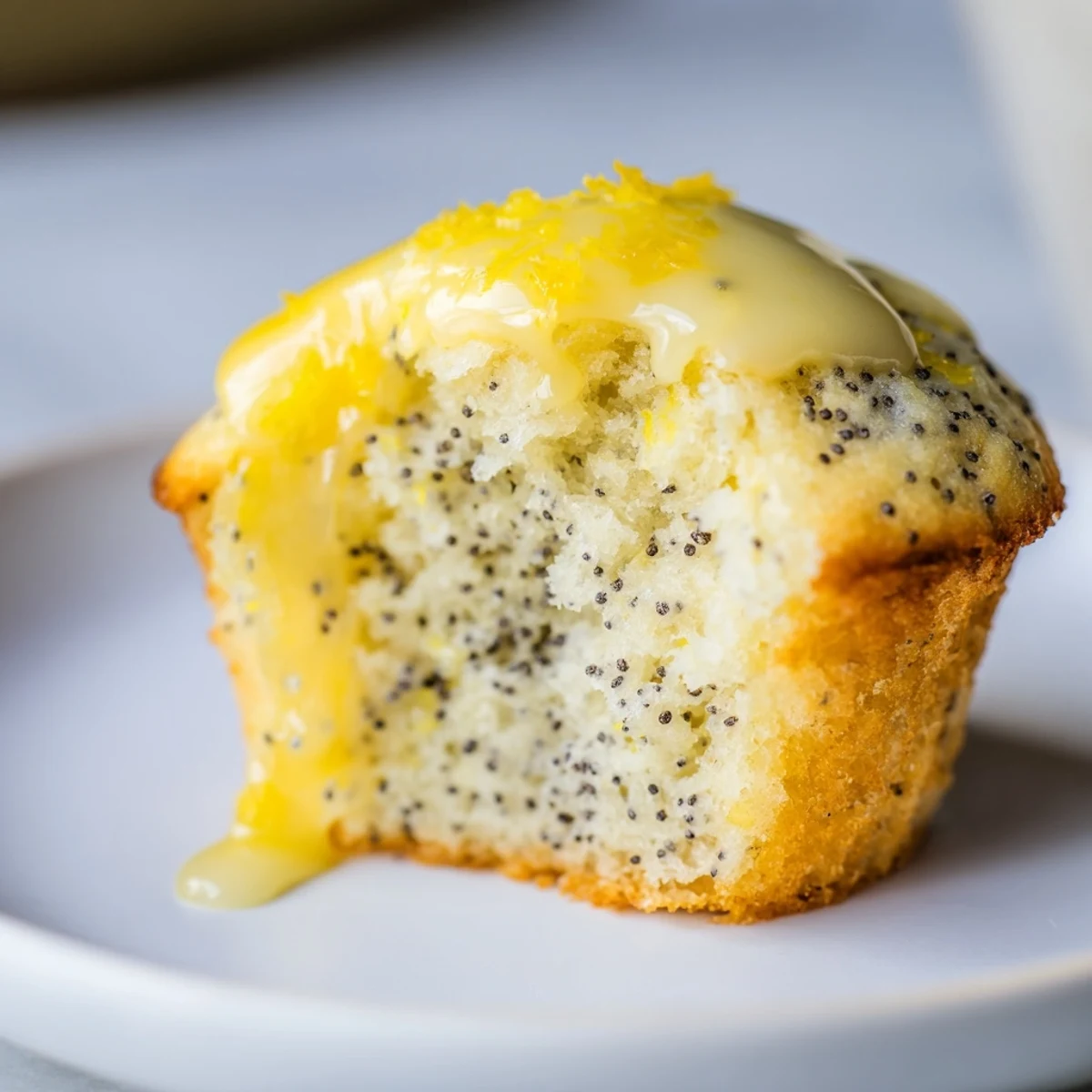 A platter of Lemon Poppy Seed Muffins with a generous lemon glaze drizzle, ready to be served with a hot cup of tea.