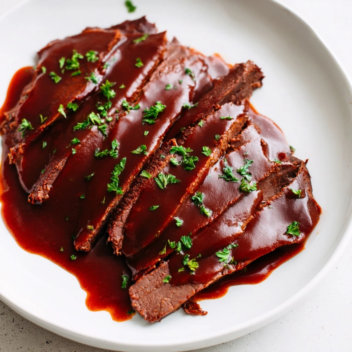 Fork-tender Slow Cooker Beef Brisket with BBQ Sauce on a plate, glistening with sweet and smoky glaze, ready for dinner.
