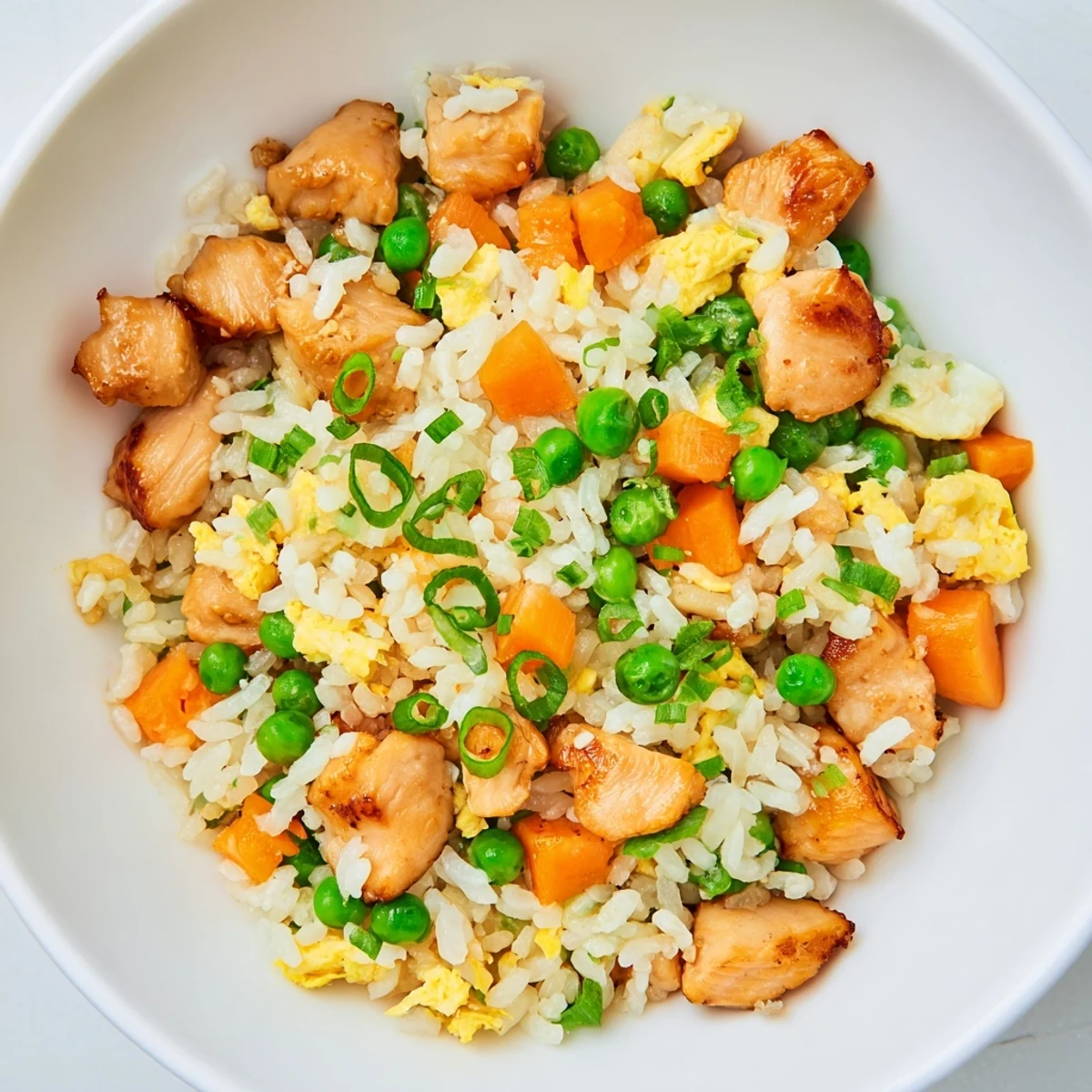 Overhead shot of sizzling Chicken Fried Rice with Peas and Carrots, with vibrant peas and carrots mixed throughout the savory, golden-colored jasmine rice.