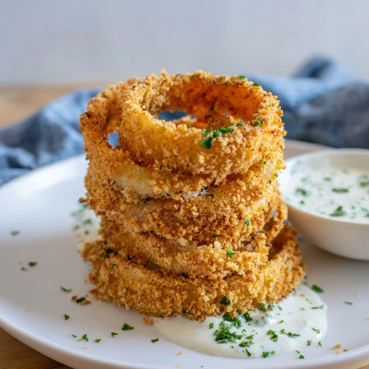 Freshly baked Crispy Baked Onion Rings with Ranch are served on parchment with chives for garnish.