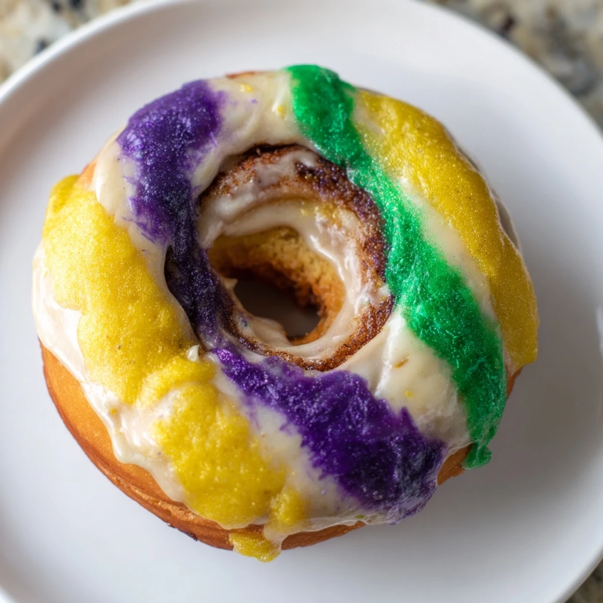 Glazed Mardi Gras King Cake Donuts stacked on a plate, showcasing a cinnamon swirl interior and festive Mardi Gras colors.