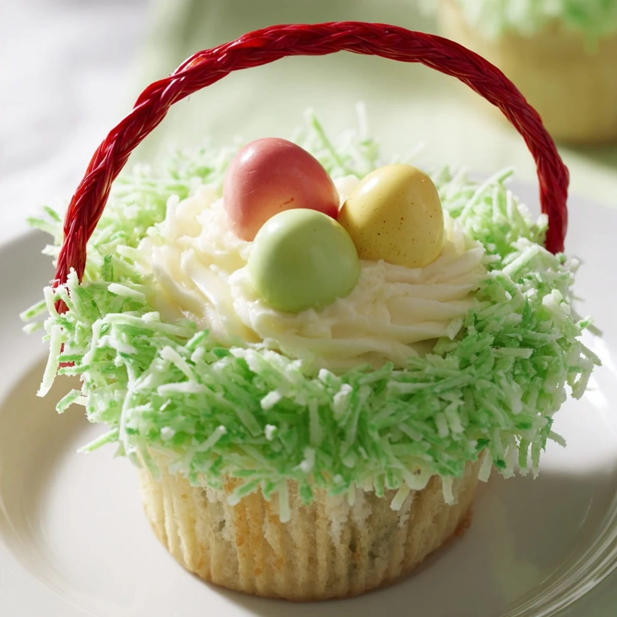 Moist vanilla Easter Basket Cupcakes with green coconut grass and candy egg toppings on a pastel plate.