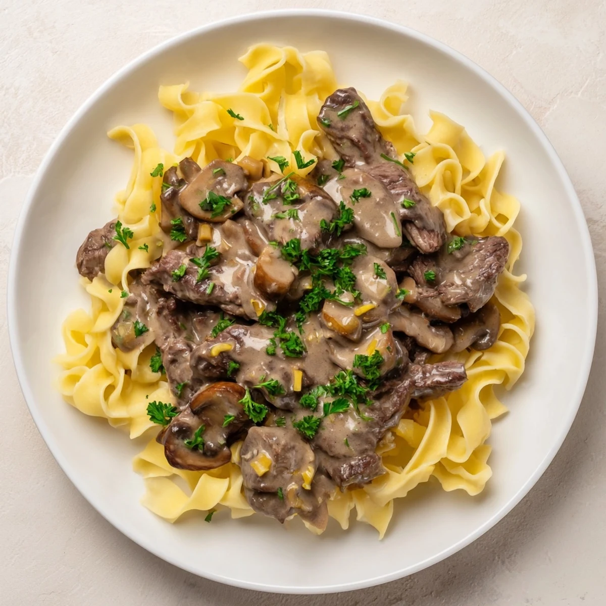 Hearty Beef Stroganoff with Egg Noodles served steaming hot, garnished with fresh parsley on a cozy dinner plate.