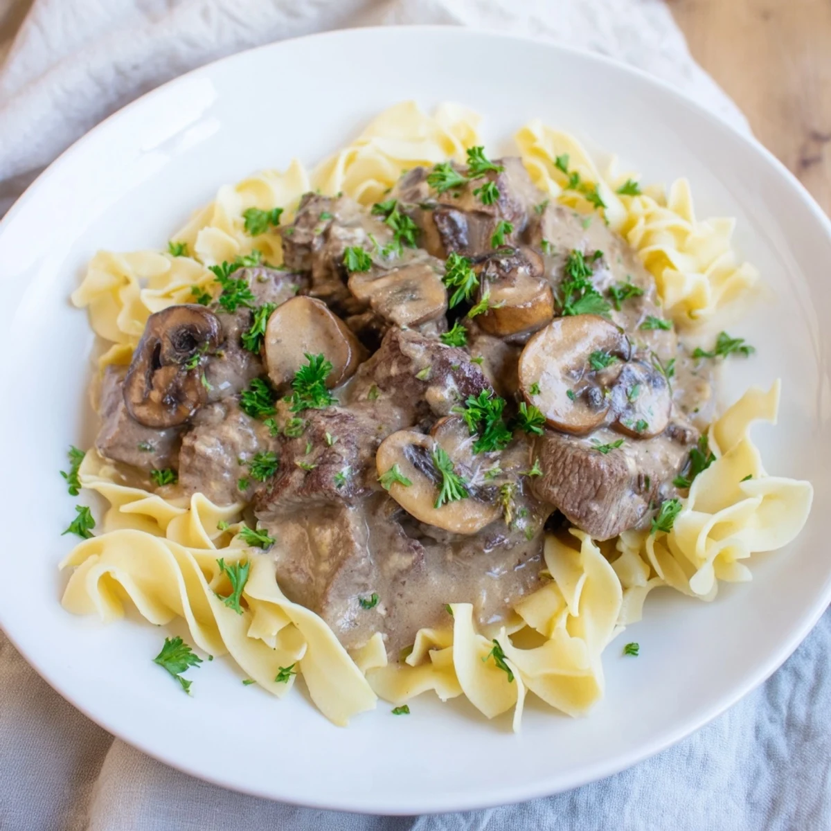 Close-up view of a comforting bowl of Beef Stroganoff with Egg Noodles, showcasing the savory sauce and glossy noodles ready to eat.