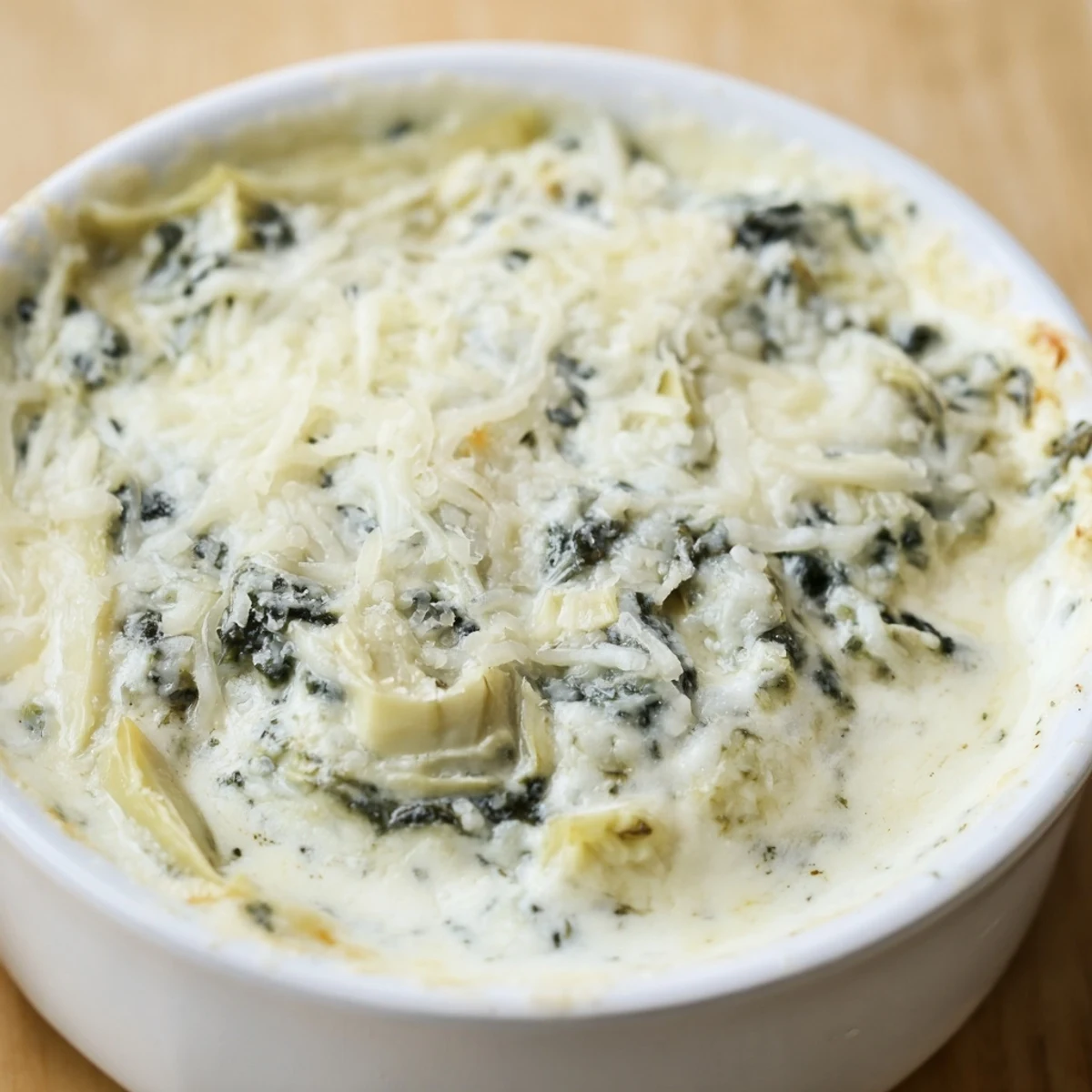 Steaming Creamy Spinach and Artichoke Dip with Chips topped with melted cheese beside a basket of chips.