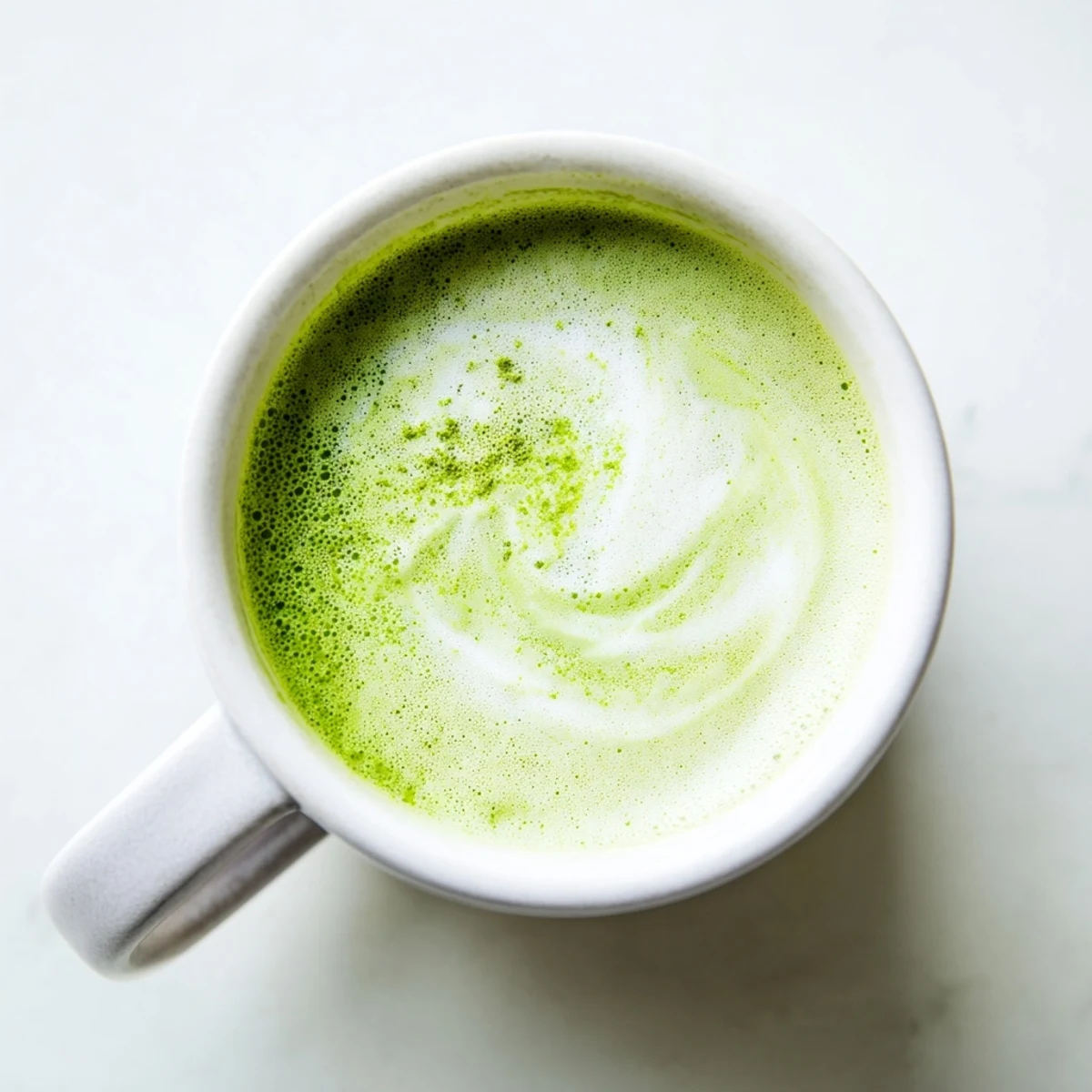 Close-up view of a Green Matcha Latte with Almond Milk, highlighting the silky microfoam and the earthy, bright green tea hue.