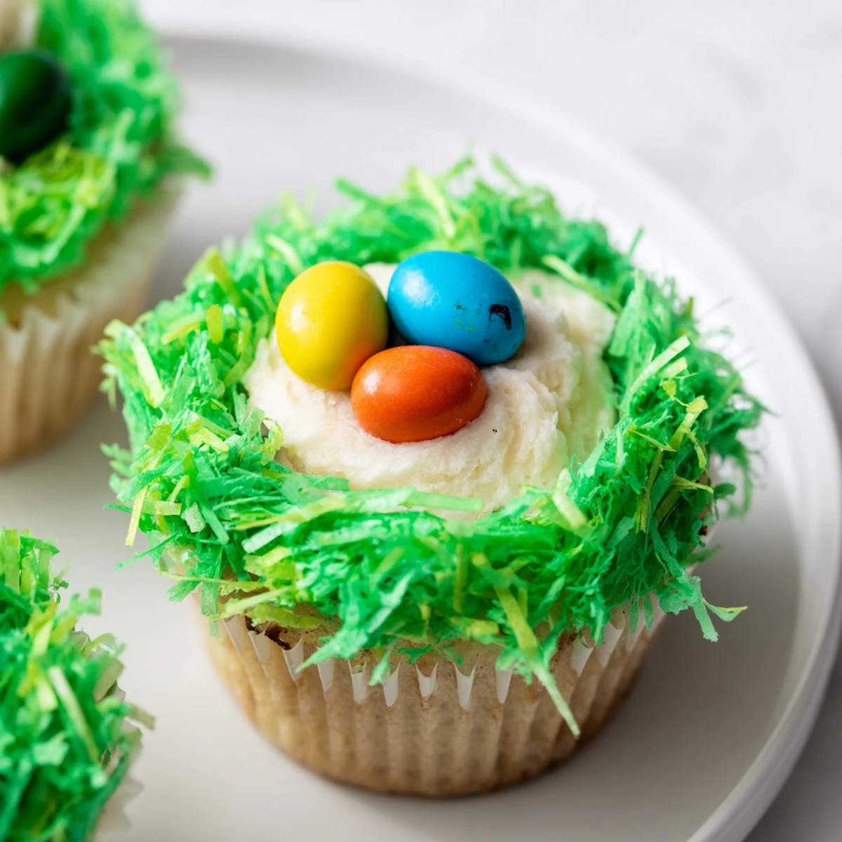 Easter Basket Cupcakes feature fluffy frosting, green shredded coconut, and colorful eggs ready to serve.