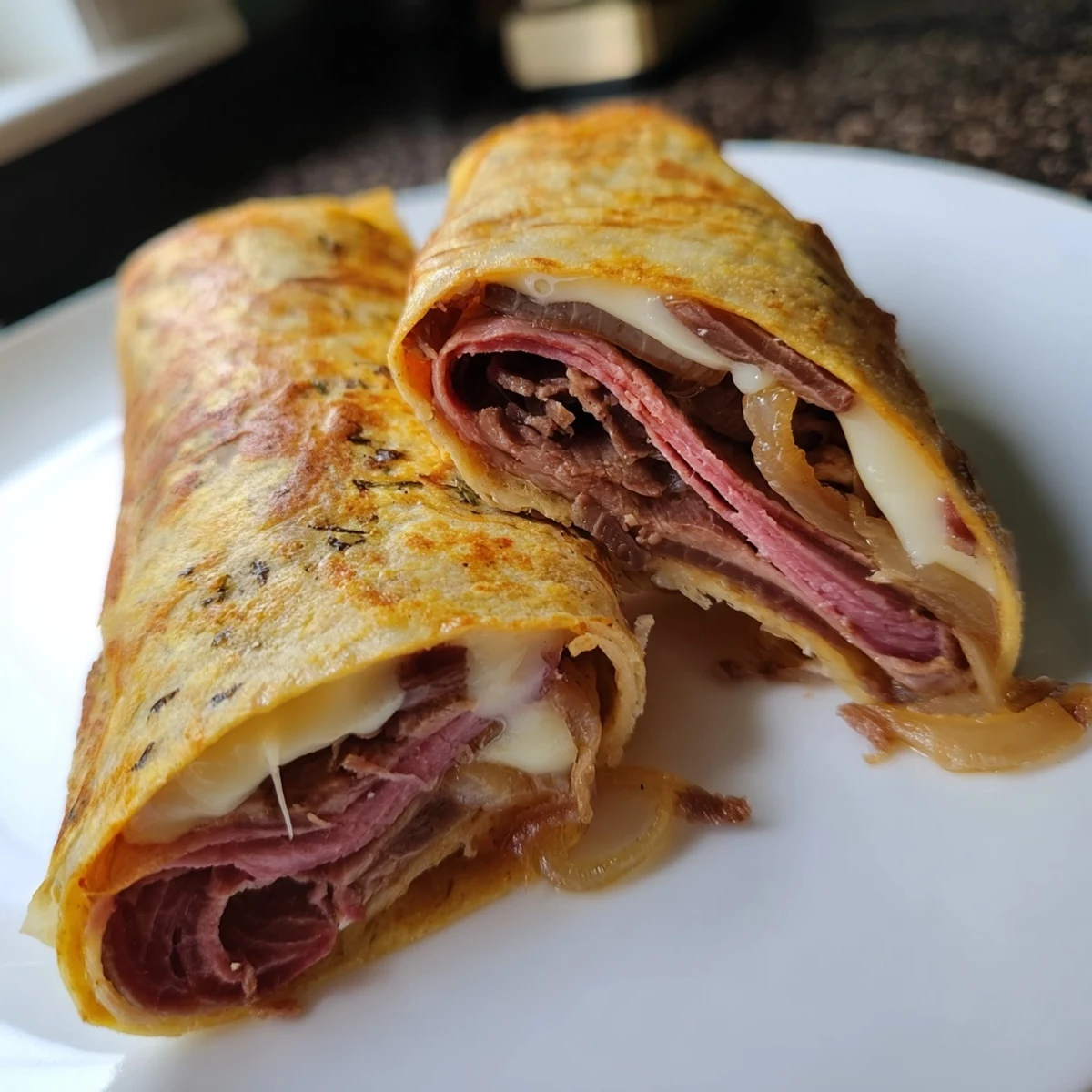 Close-up of Easy French Dip Tortilla Roll Ups, featuring caramelized onions and tender roast beef wrapped in a crisp tortilla.
