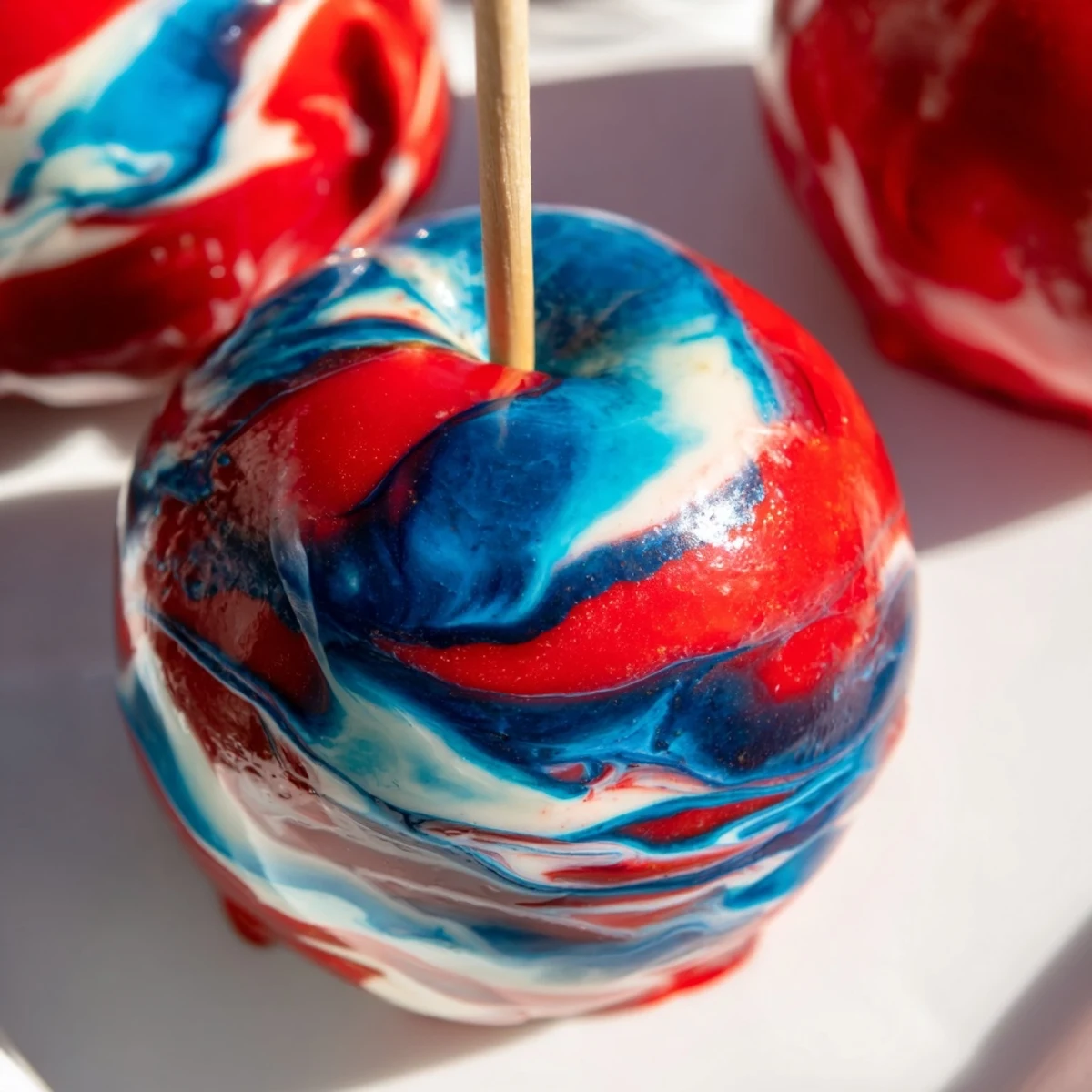 Glistening marbled effect candy apples sit on a parchment-lined tray, highlighting the vibrant, artistic candy coating sheen.