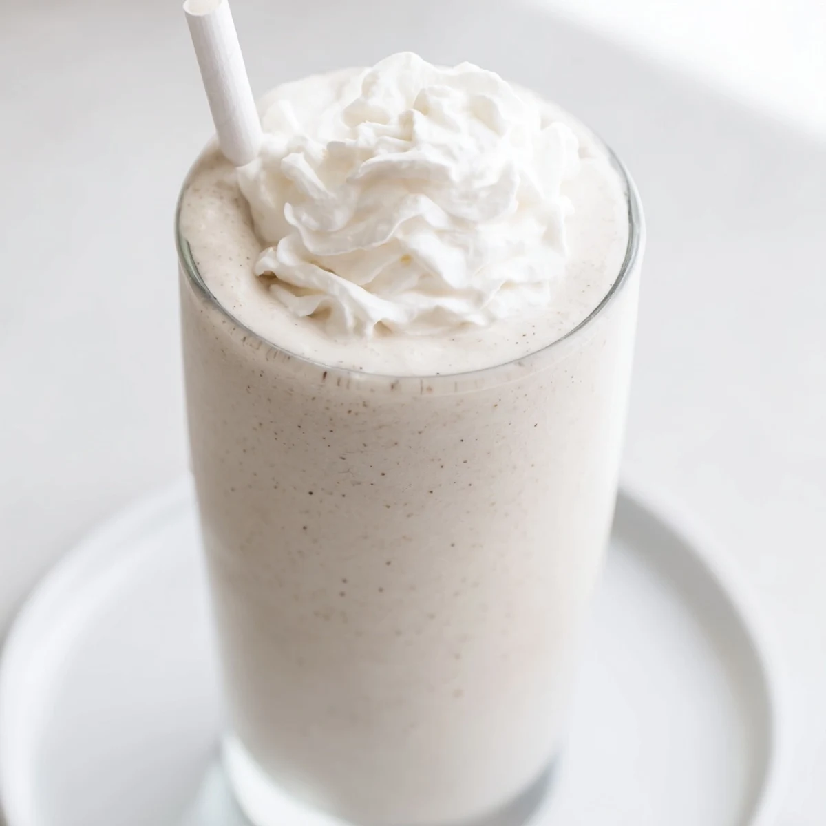 Aerial view of two homemade Starbucks Vanilla Bean Frappuccino drinks with straws and a dusting of vanilla bean powder.