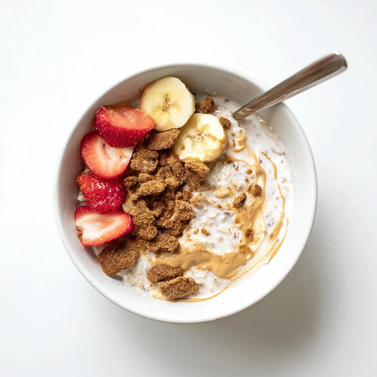 Creamy Quick Biscoff Overnight Oats topped with crushed cookies and fresh berries in a glass jar.