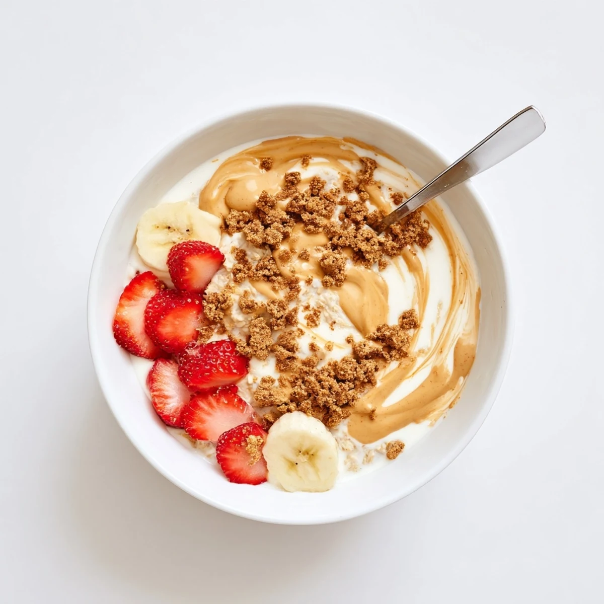 A spoon scoops into creamy Quick Biscoff Overnight Oats with a drizzle of melted spread.