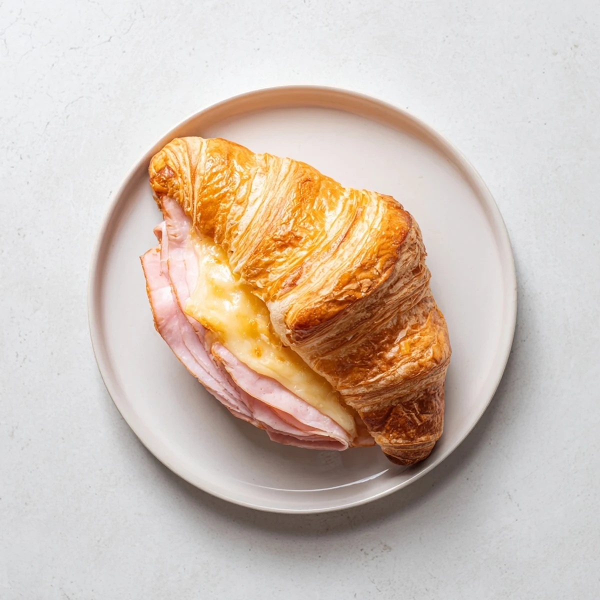 Warm Ham and Cheese Croissant on a rustic plate, ready for brunch with a side of fresh fruit.