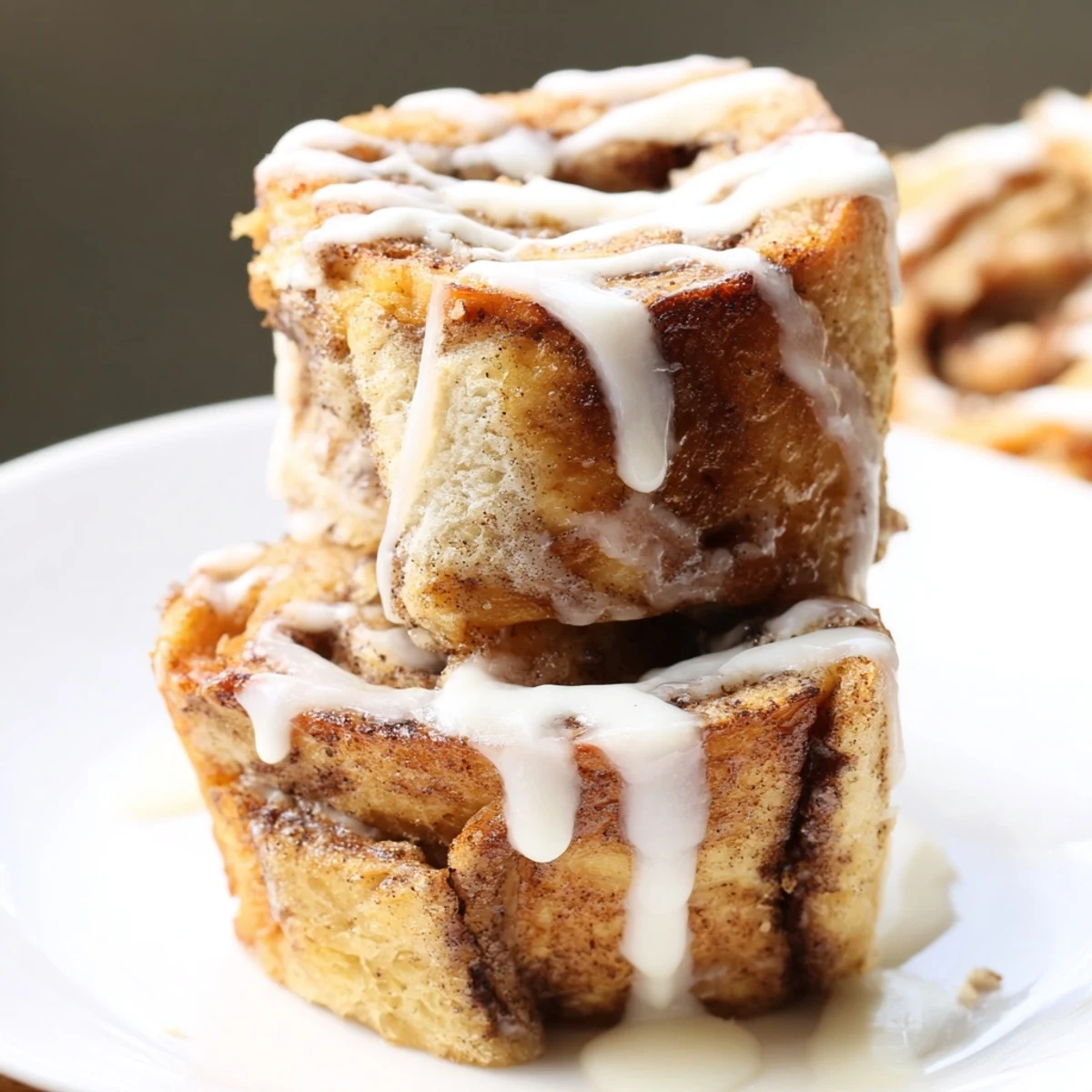 Decadent, bite-sized Cinnamon Roll French Toast Bites stacked high and ready for brunch with a side of berries.
