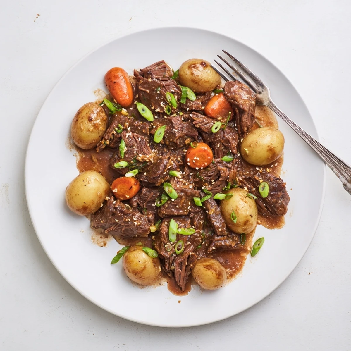 Tender shredded beef in Slow Cooker Korean Beef Pot Roast With Soy Garlic Gravy over steamed rice with sesame seeds.
