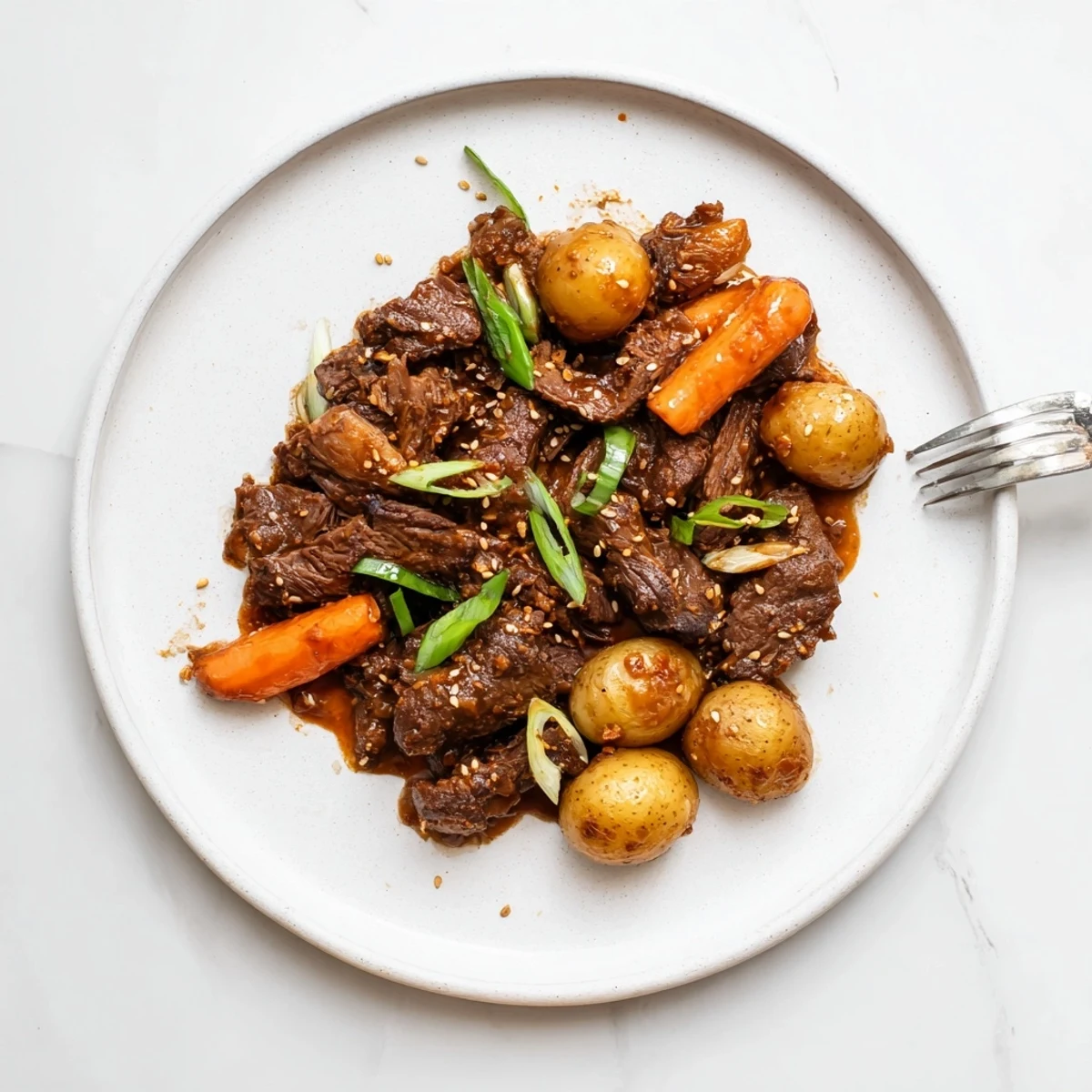 Fork-tender Slow Cooker Korean Beef Pot Roast With Soy Garlic Gravy served with carrots and potatoes on a platter.