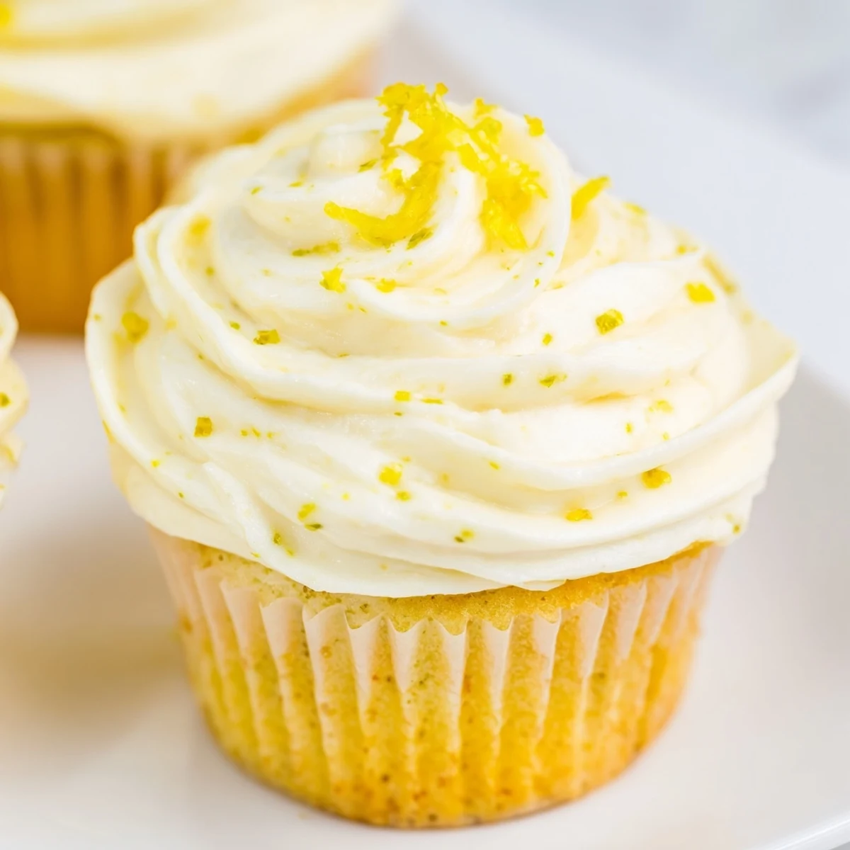 Limoncello Cupcakes arranged on a white serving platter, paired with lemon slices and a small glass of Limoncello for a festive spring gathering.