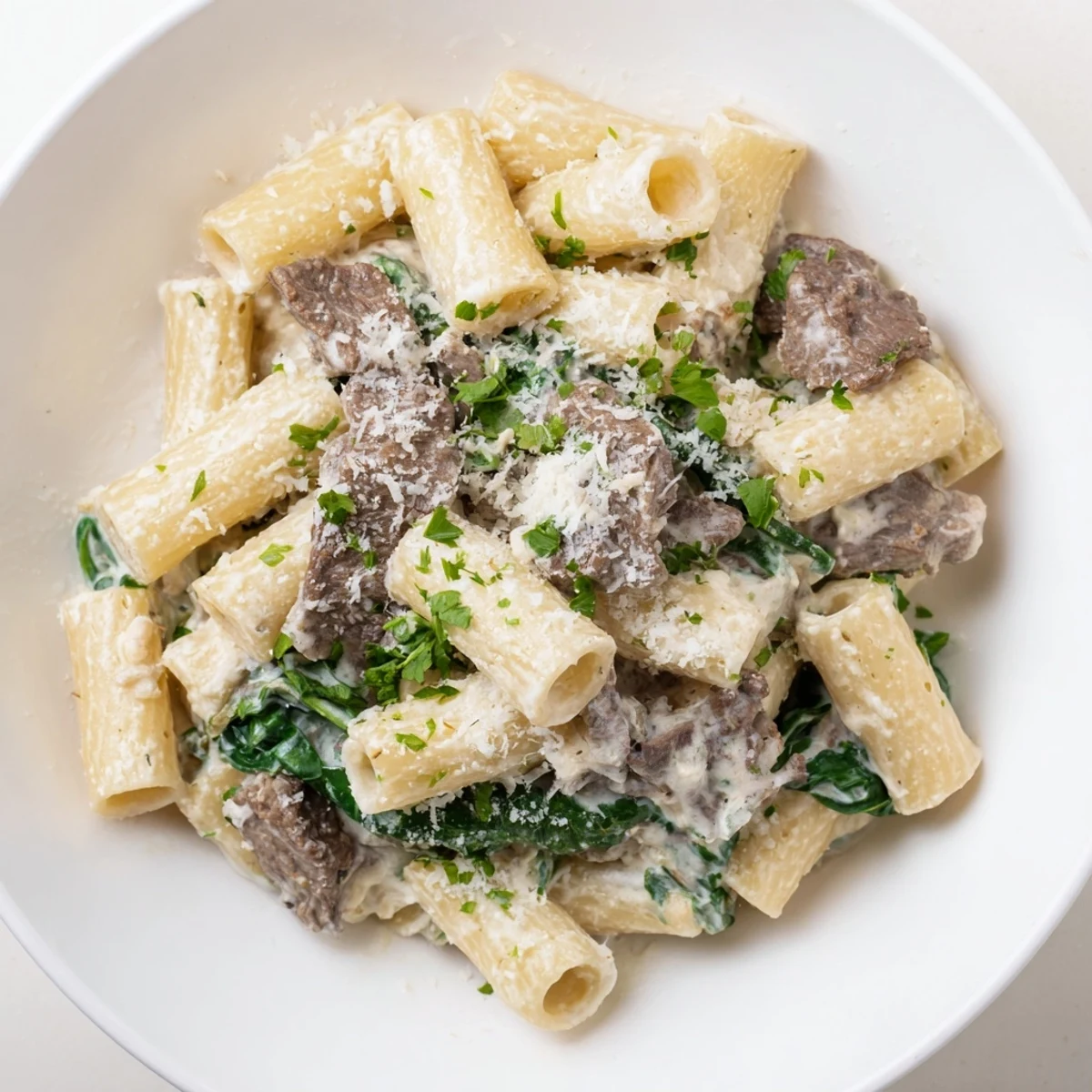 High protein beef pasta featuring browned beef strips, wilted spinach, and a velvety yogurt cottage cheese sauce coating al dente pasta