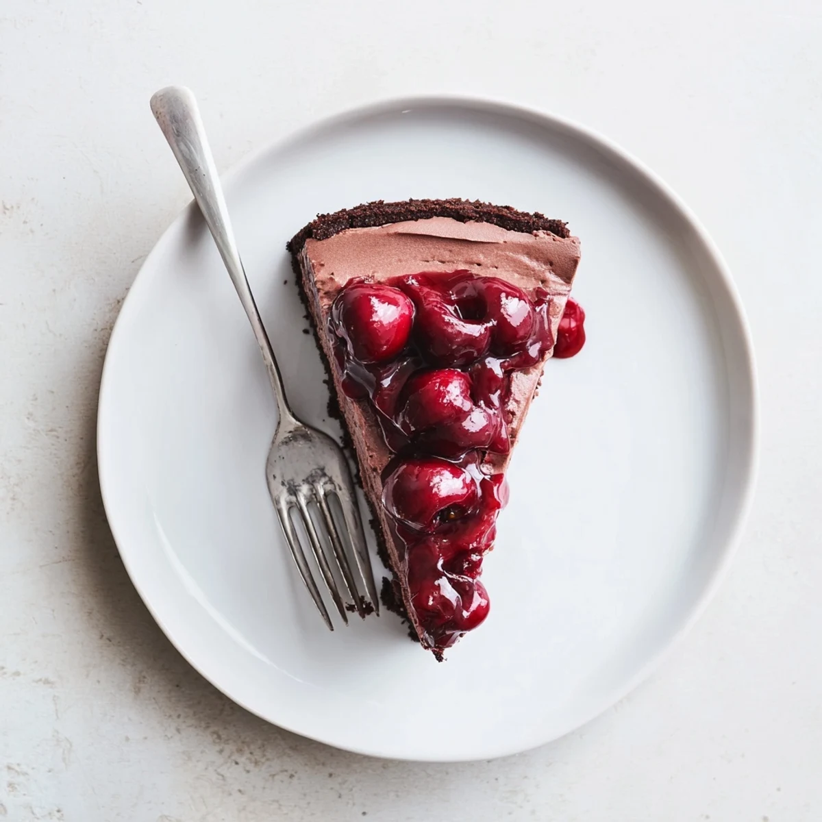Decadent dark chocolate cherry cheesecake featuring layers of chocolate custard filling and vibrant cherry compote garnish