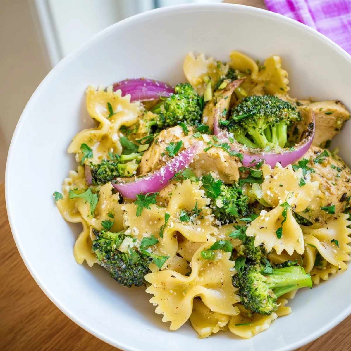 Hearty bowl of cowboy butter lemon chicken bowtie pasta garnished with fresh herbs and grated Parmesan cheese