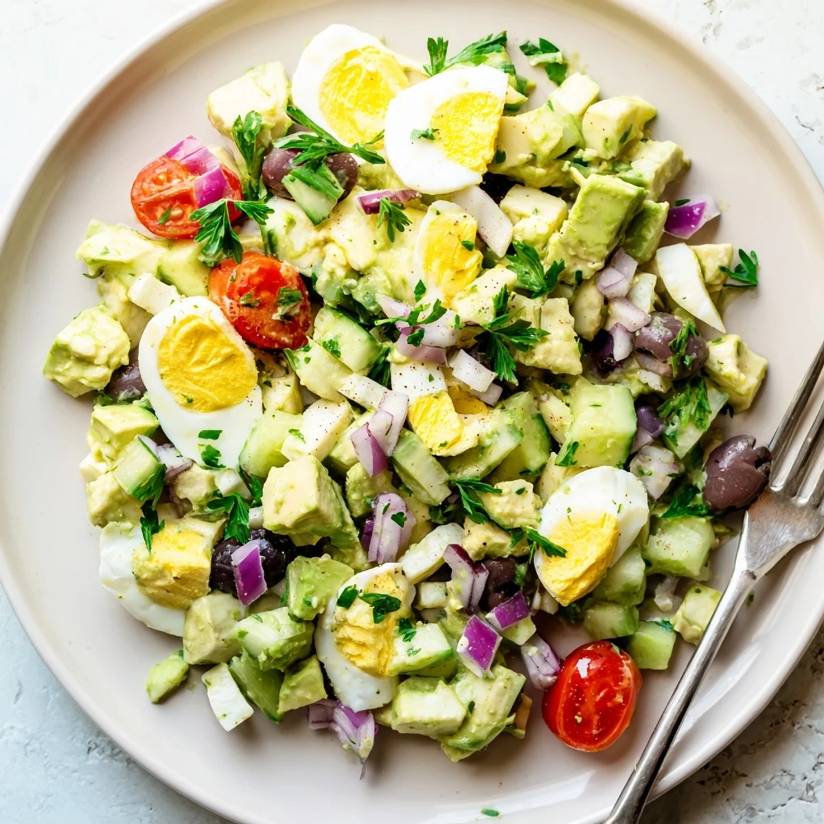 Zesty egg salad with ripe avocado, Kalamata olives, and crisp red onion on a wooden board
