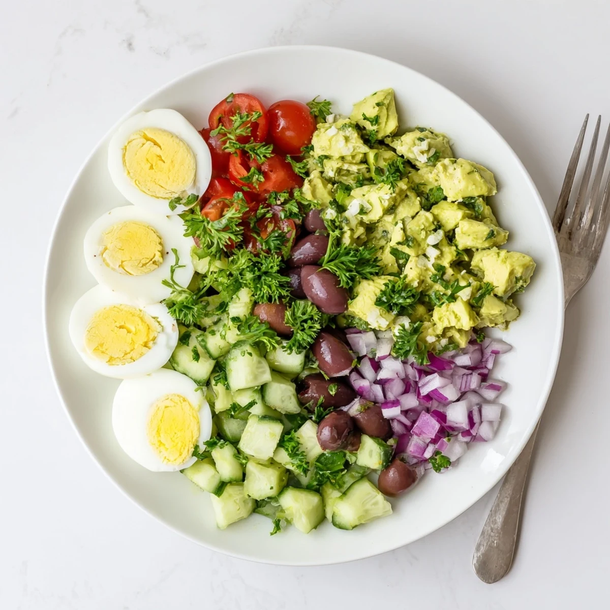 Simple Mediterranean avocado egg salad plated with cucumber chunks and bright lemon dressing