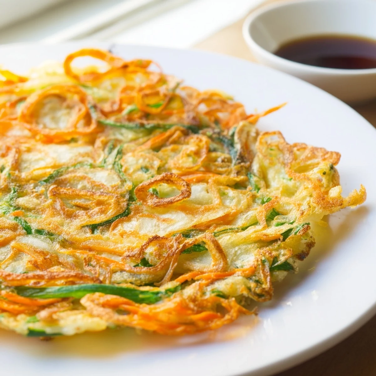 Plate of hot Korean pancakes sliced into wedges served with soy dipping sauce