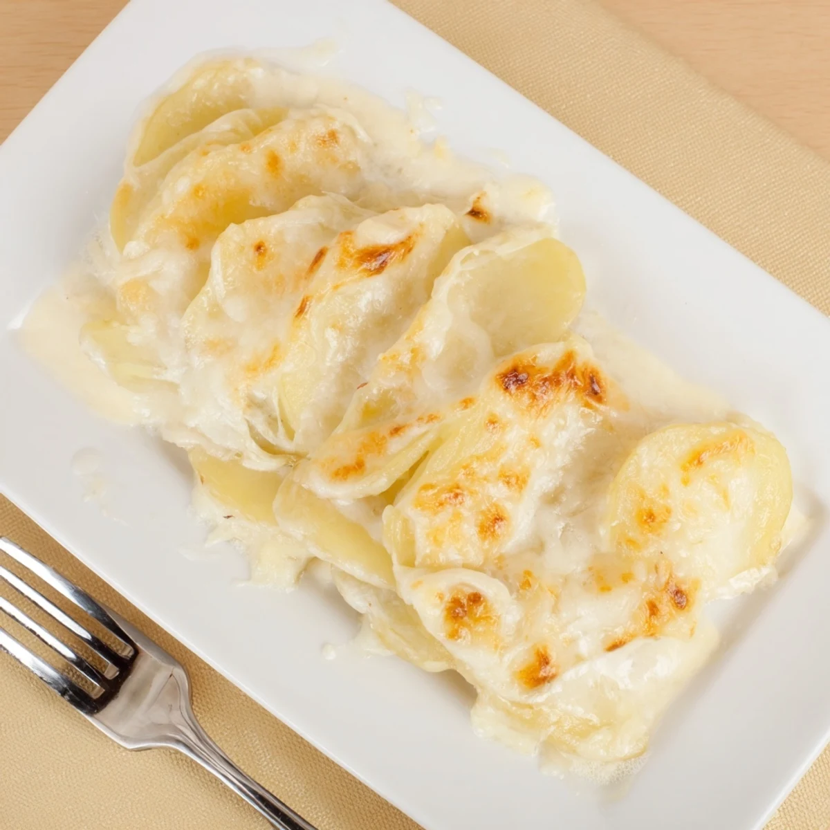 Golden brown cheesy scalloped potatoes layered in creamy sauce bubbling in a baking dish
