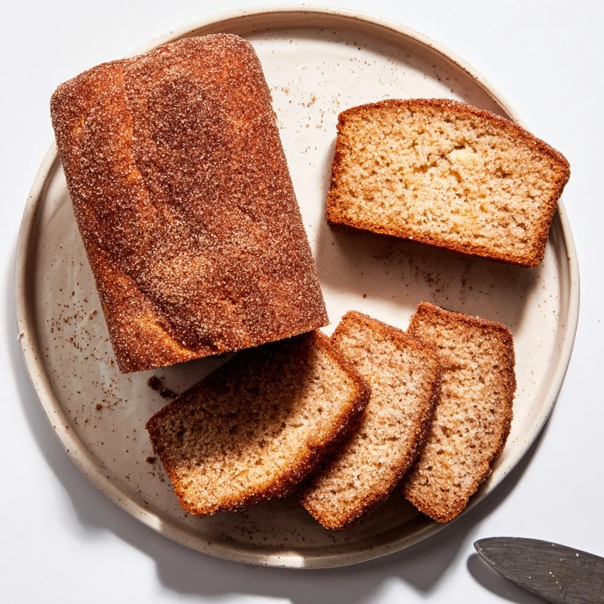 Golden cinnamon sugar donut bread loaf with crackly topping sliced on a wooden board