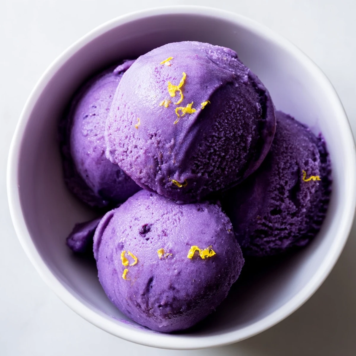 Creamy dairy-free no churn blueberry lemon sorbet served in vintage dessert glass with lemon wedge on side