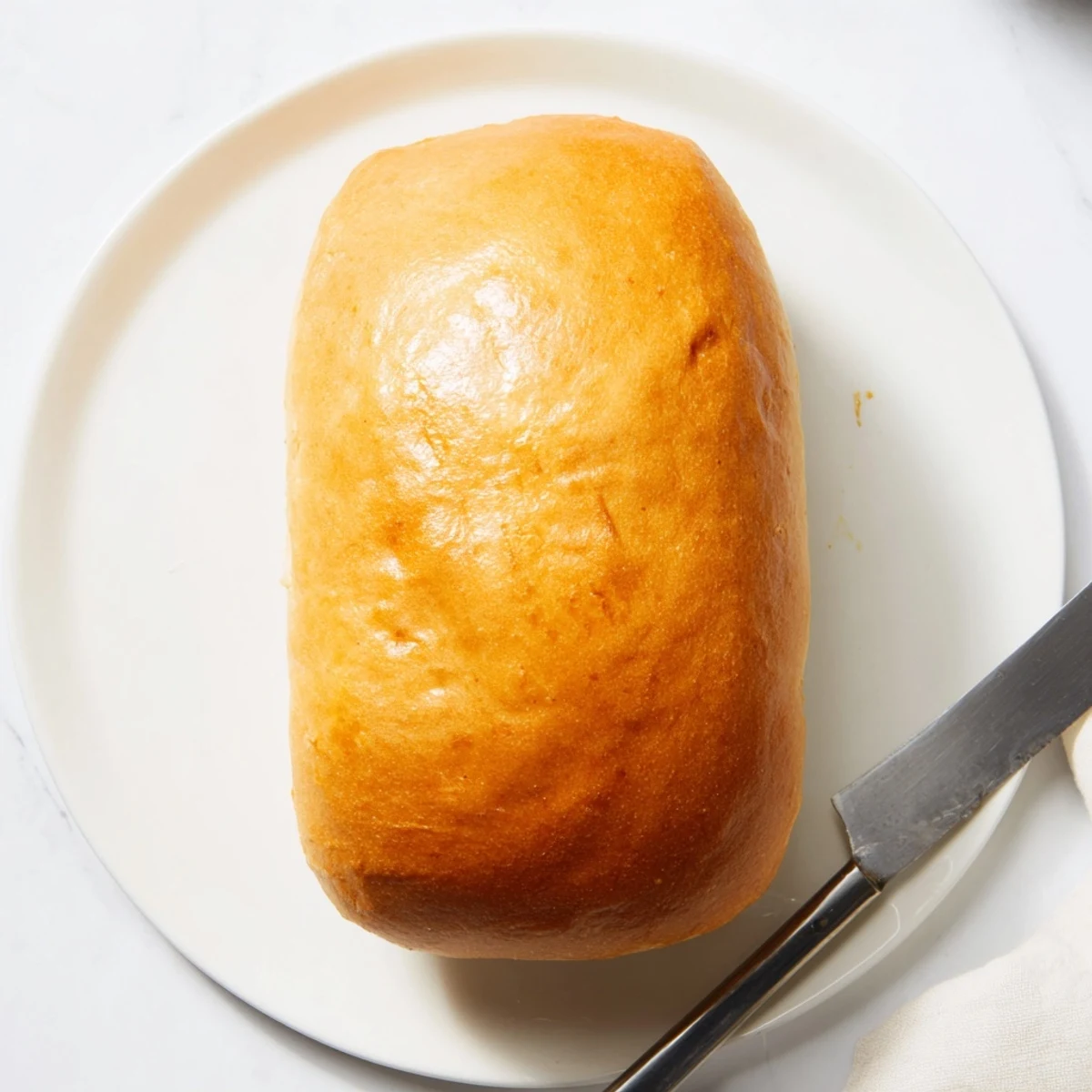 Golden brown homemade Amish white bread loaf with soft interior ready for slicing
