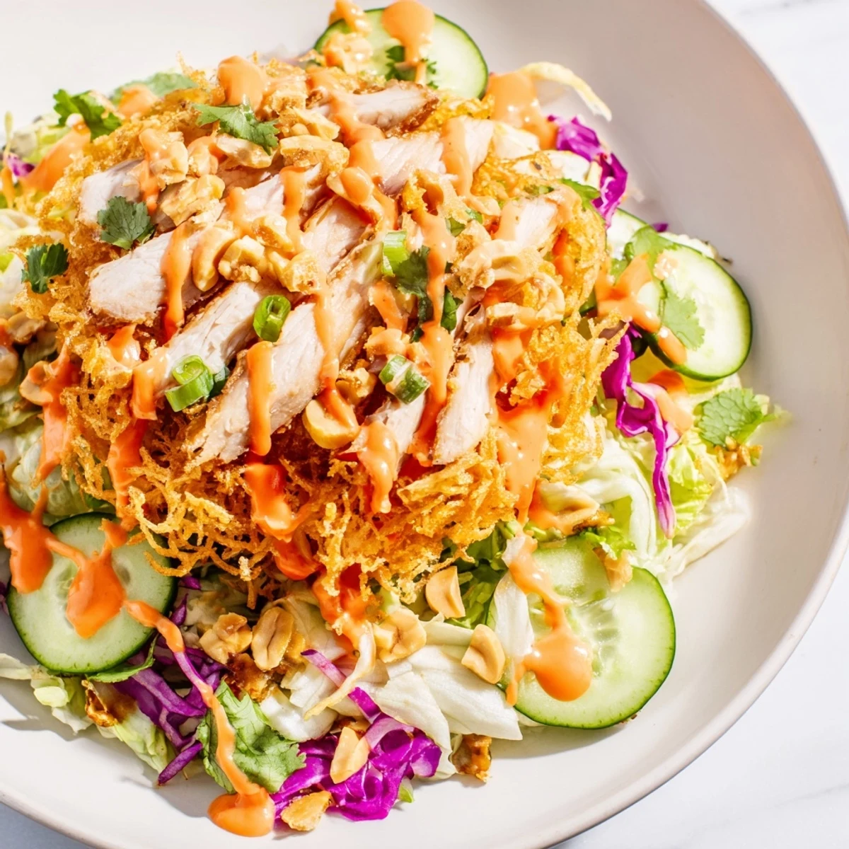 Tender sliced chicken tops vibrant vegetables and crunchy crispy rice in Bang Bang Chicken Salad