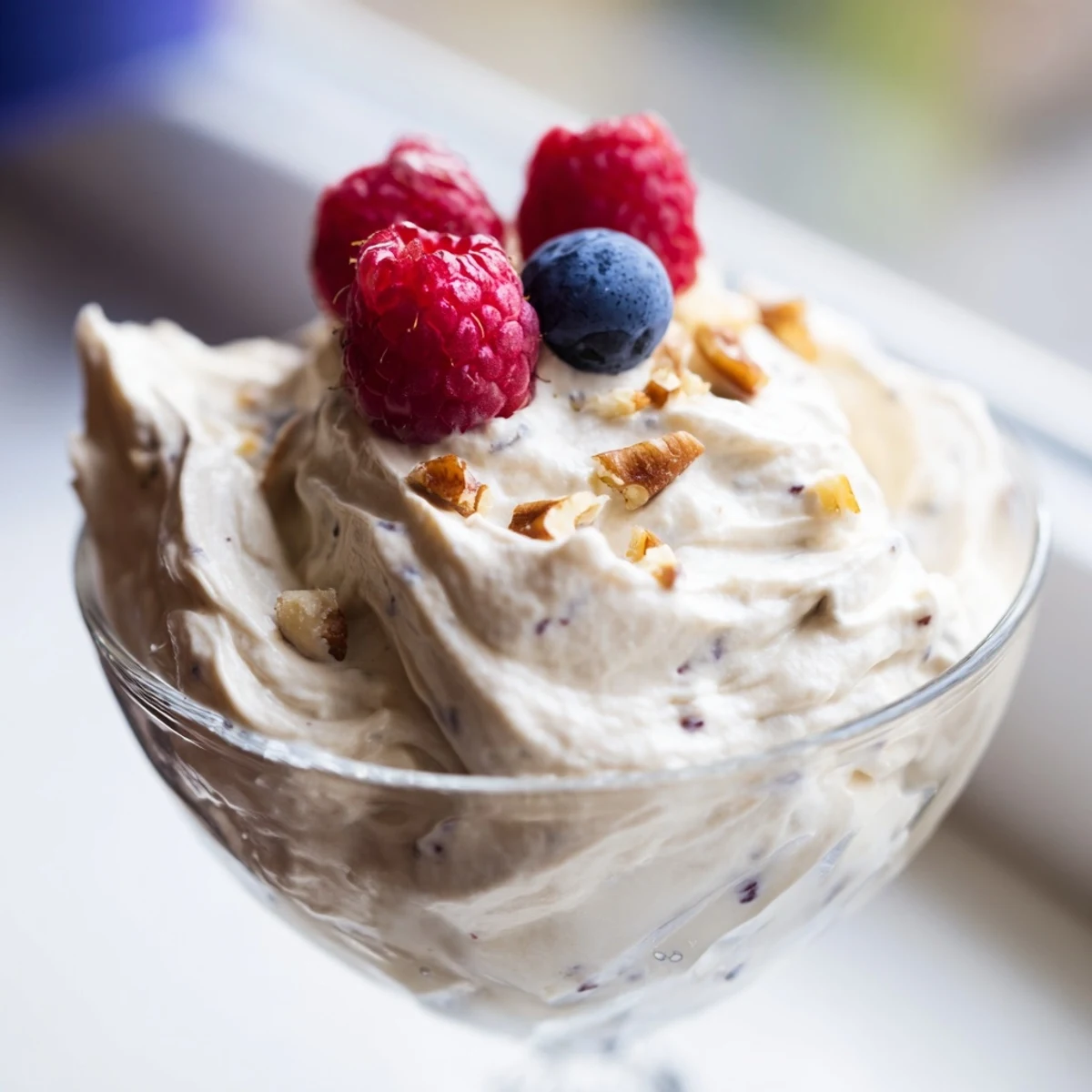 Light and airy keto cheesecake fluff swirling with whipped cream in a serving bowl