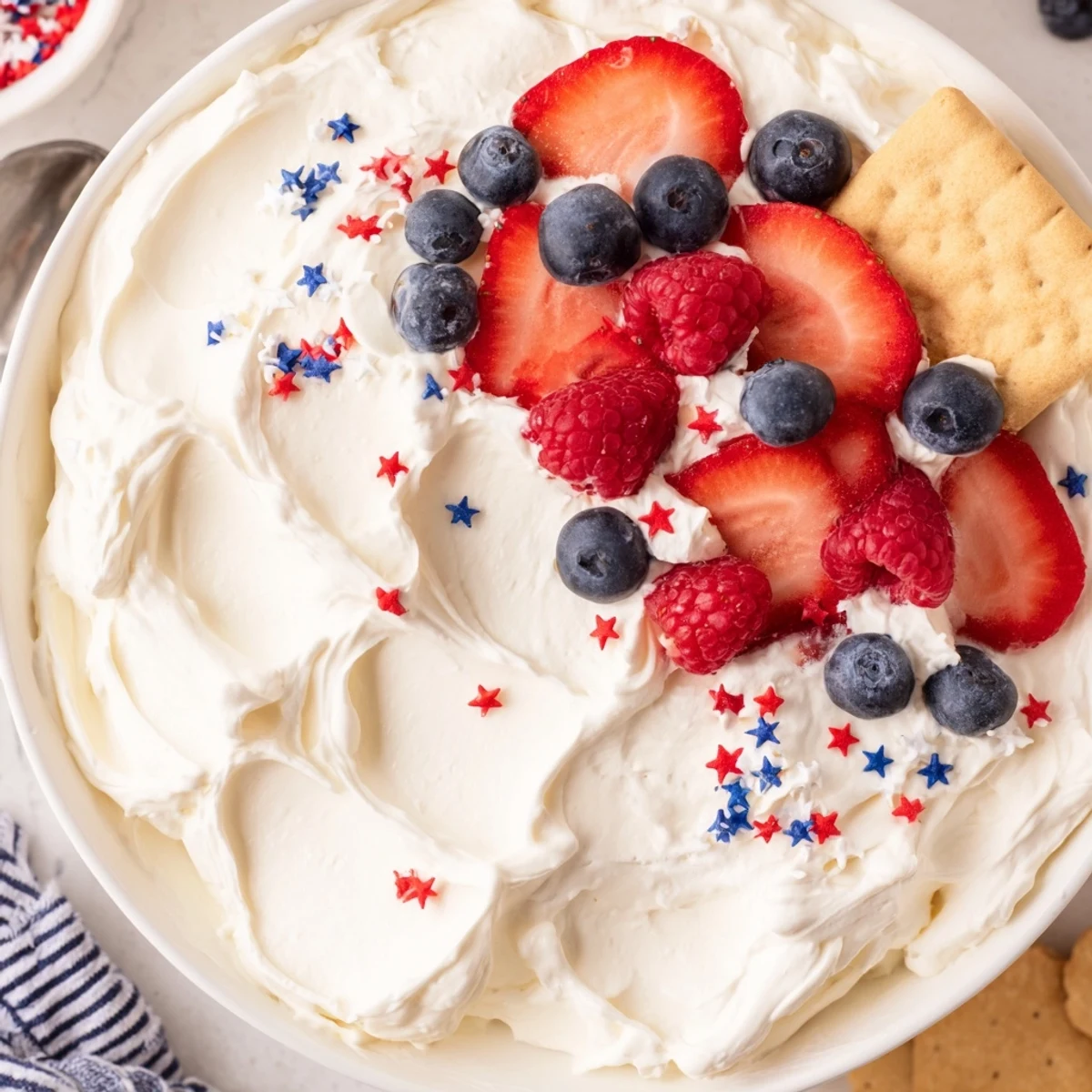 Creamy Star Spangled Cheesecake Dip topped with berries and crunchy graham crackers