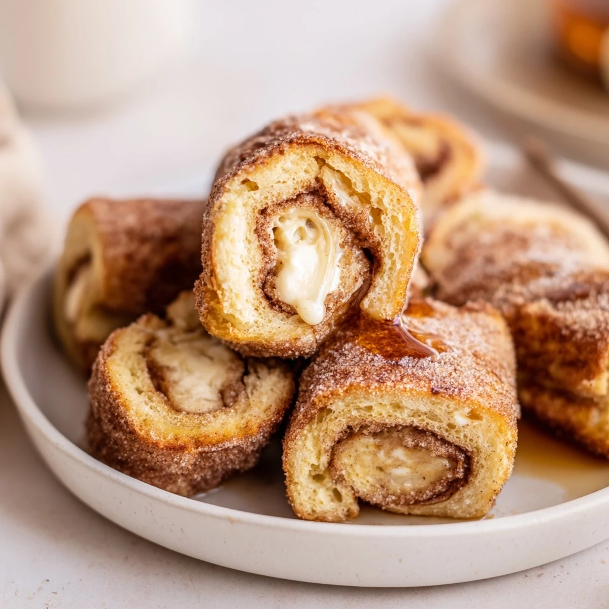 Buttery skillet-seared Cinnamon Roll French Toast Roll Ups served with maple syrup