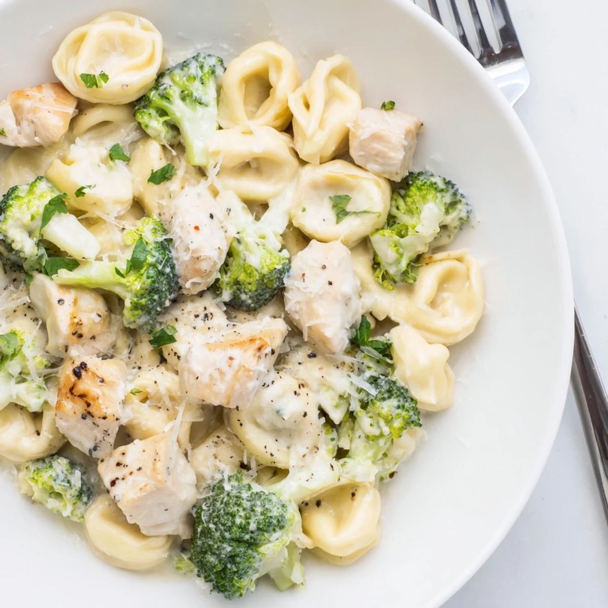 Steaming skillet of Creamy Garlic Parmesan Tortellini Chicken Broccoli Recipe with tender bites