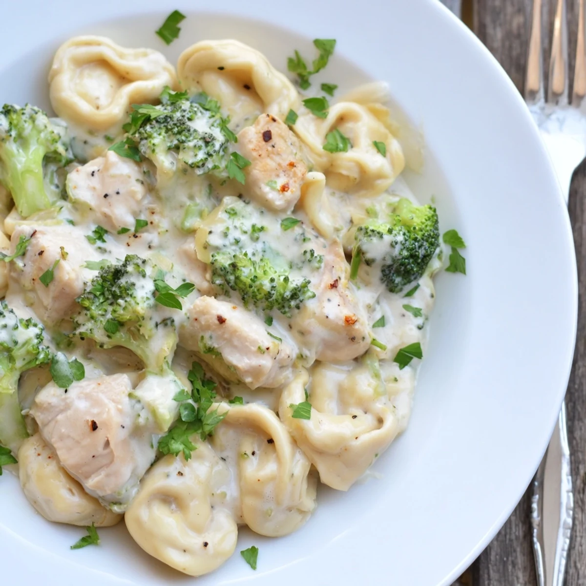 Plateful of Creamy Garlic Parmesan Tortellini Chicken Broccoli Recipe coated in silky garlic sauce