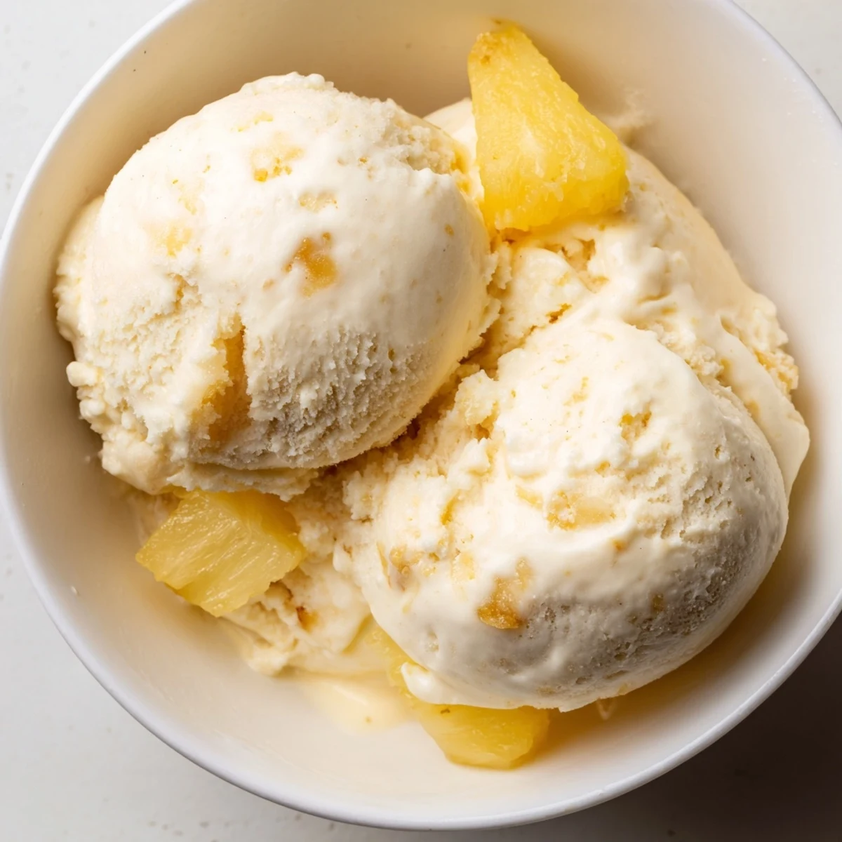 Creamy Pineapple Ice Cream served in a bowl with toasted coconut flakes