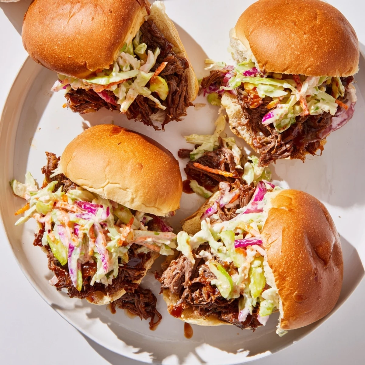 BBQ pulled beef sliders piled high with crunchy coleslaw on toasted golden brioche buns
