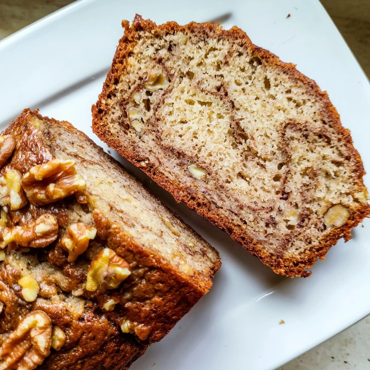 Moist banana bread with walnuts and cinnamon swirled throughout, served on a wooden cutting board